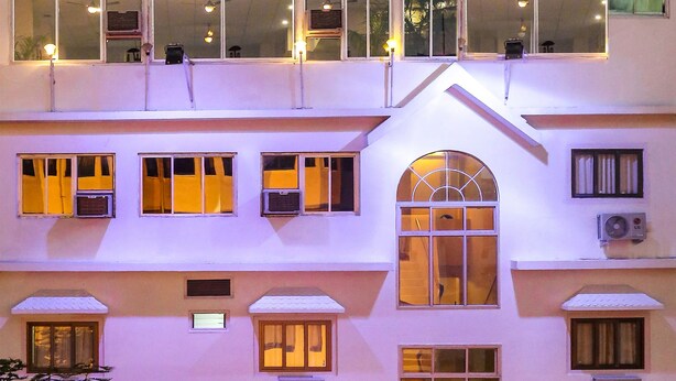 Un hotel a più piani con un ingresso centrale, condizionatori d'aria e un'insegna che indica un ristorante.