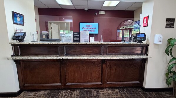 A reception desk with a digital screen displaying 'FREE Continental Breakfast'. - Red Roof Inn & Suites Commerce - Athens (Commerce)