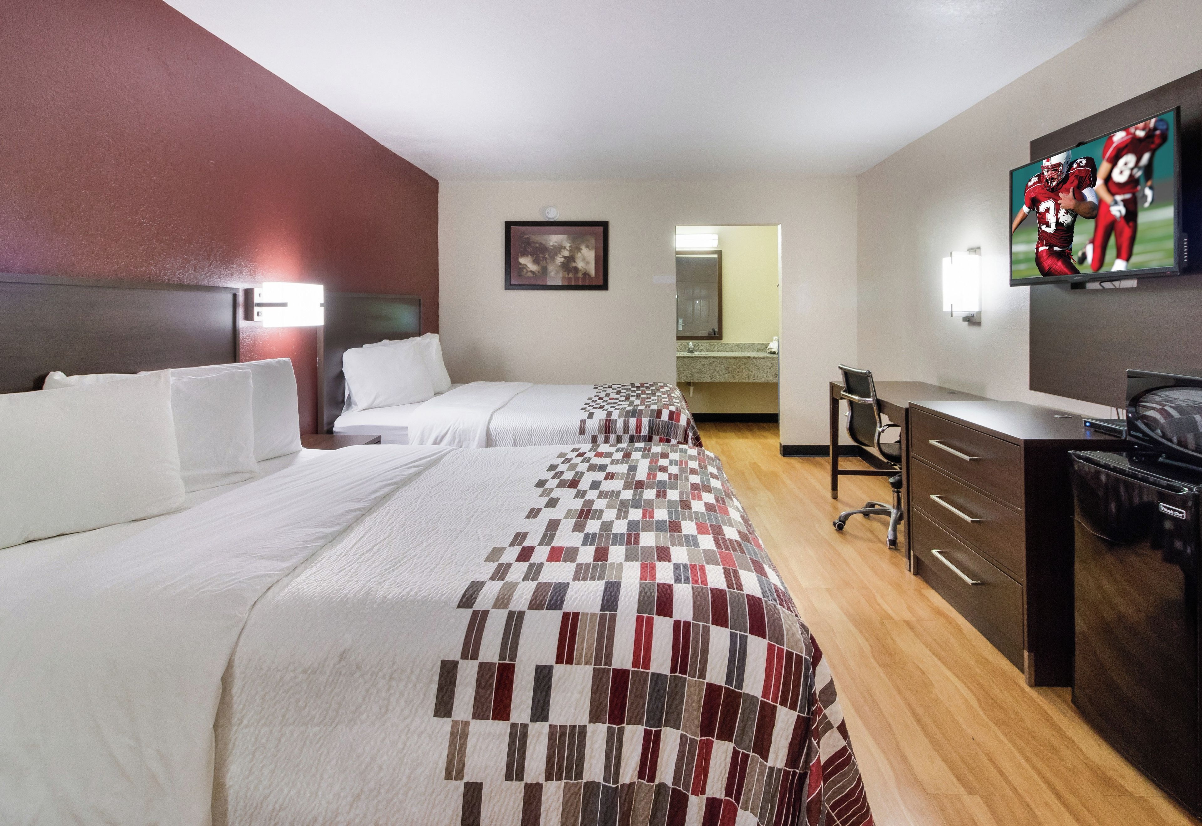 Habitación de hotel con dos camas, un escritorio, una silla, un televisor y un minibar.