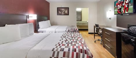 A hotel room with two beds, a desk, a chair, a television, and a minibar.