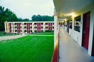 Un motel de varios pisos con un corredor cubierto y un patio con césped.