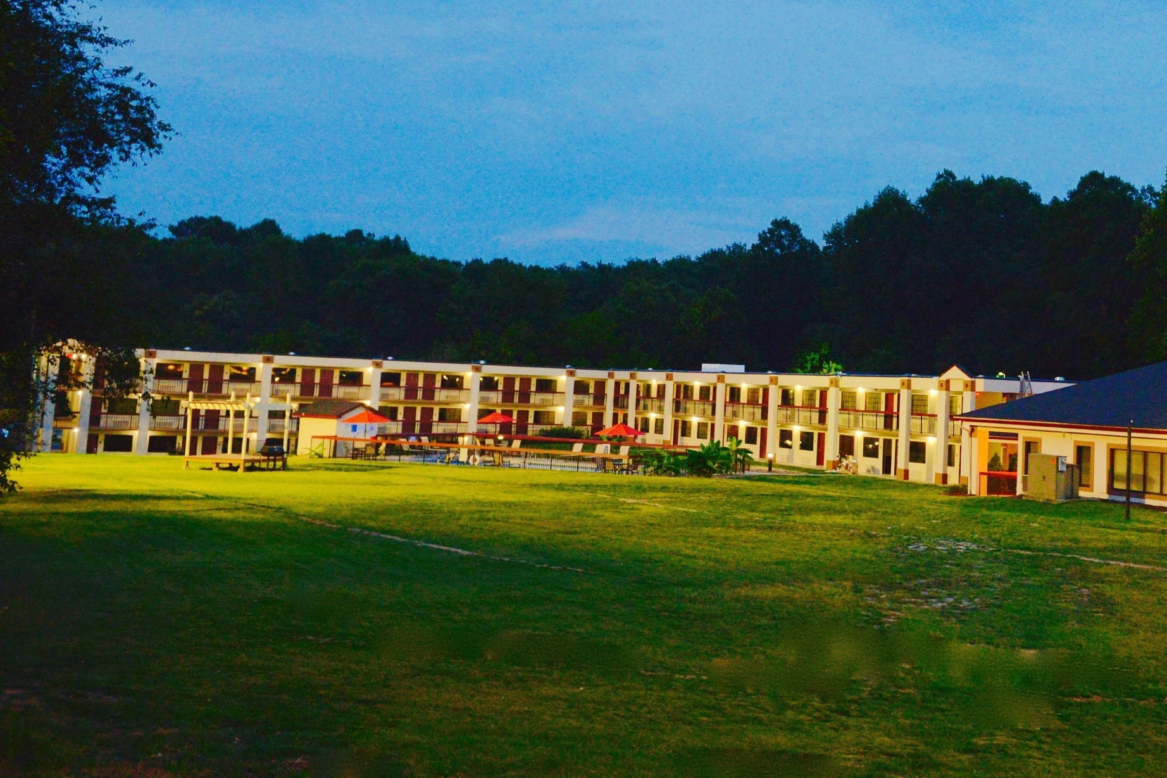 A multi-story hotel with a central courtyard, surrounded by a forested area.