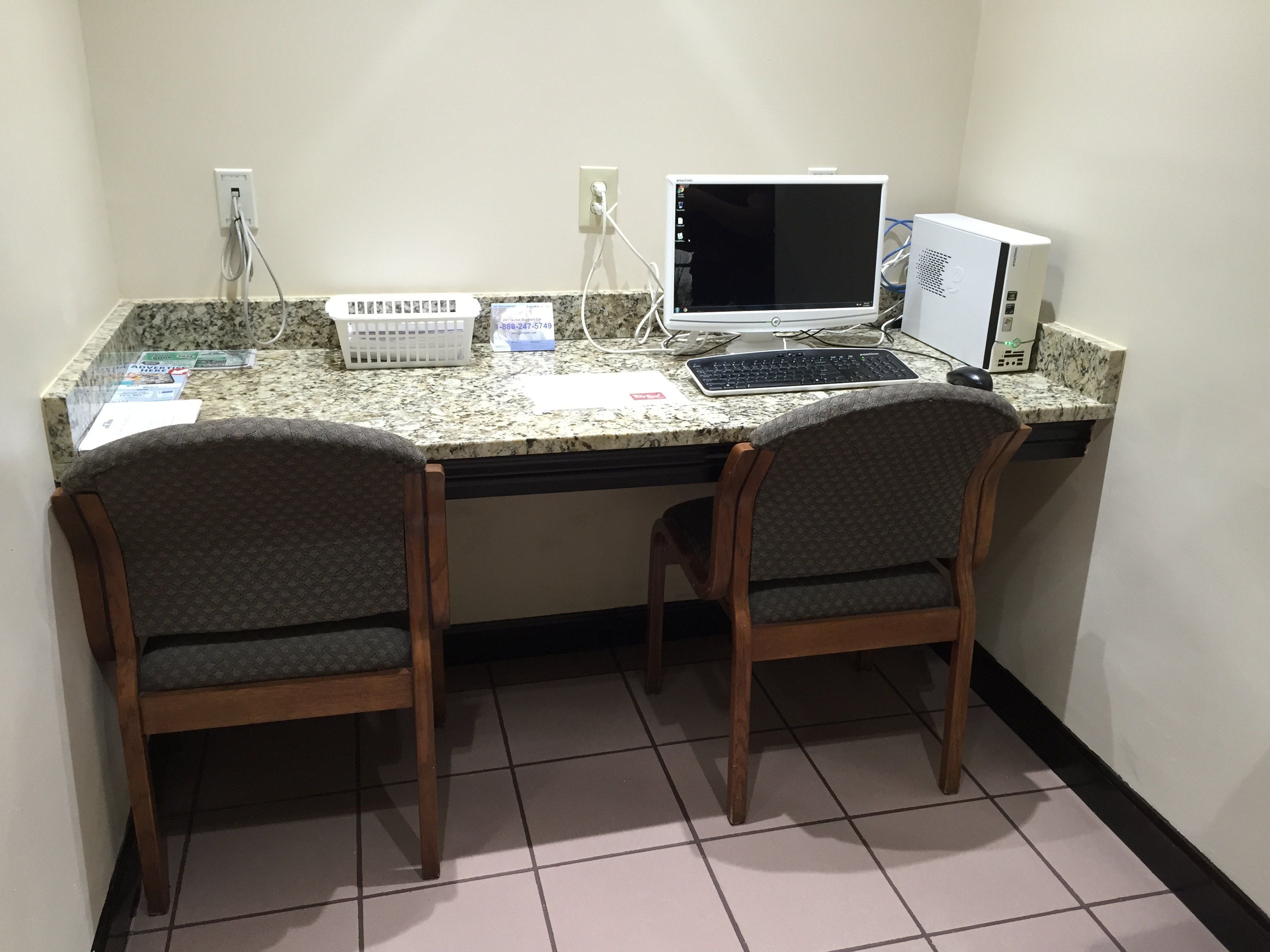 A workspace with two chairs, a desktop computer, and a monitor.
