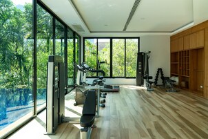 Een moderne sportschool met fitnessapparatuur, grote ramen en uitzicht op een zwembad.