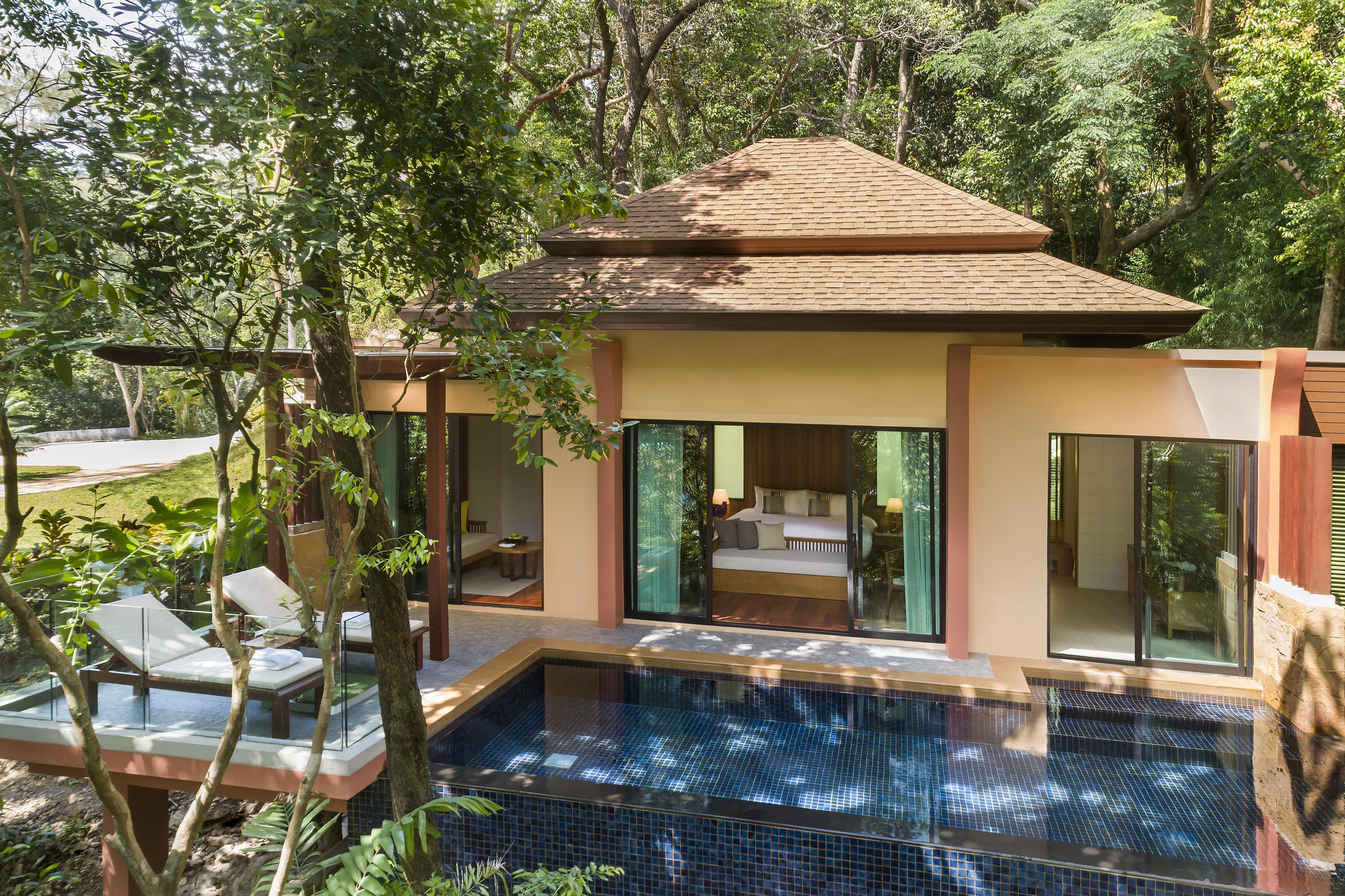A modern villa with a swimming pool, large glass doors, and a view of the surrounding greenery.