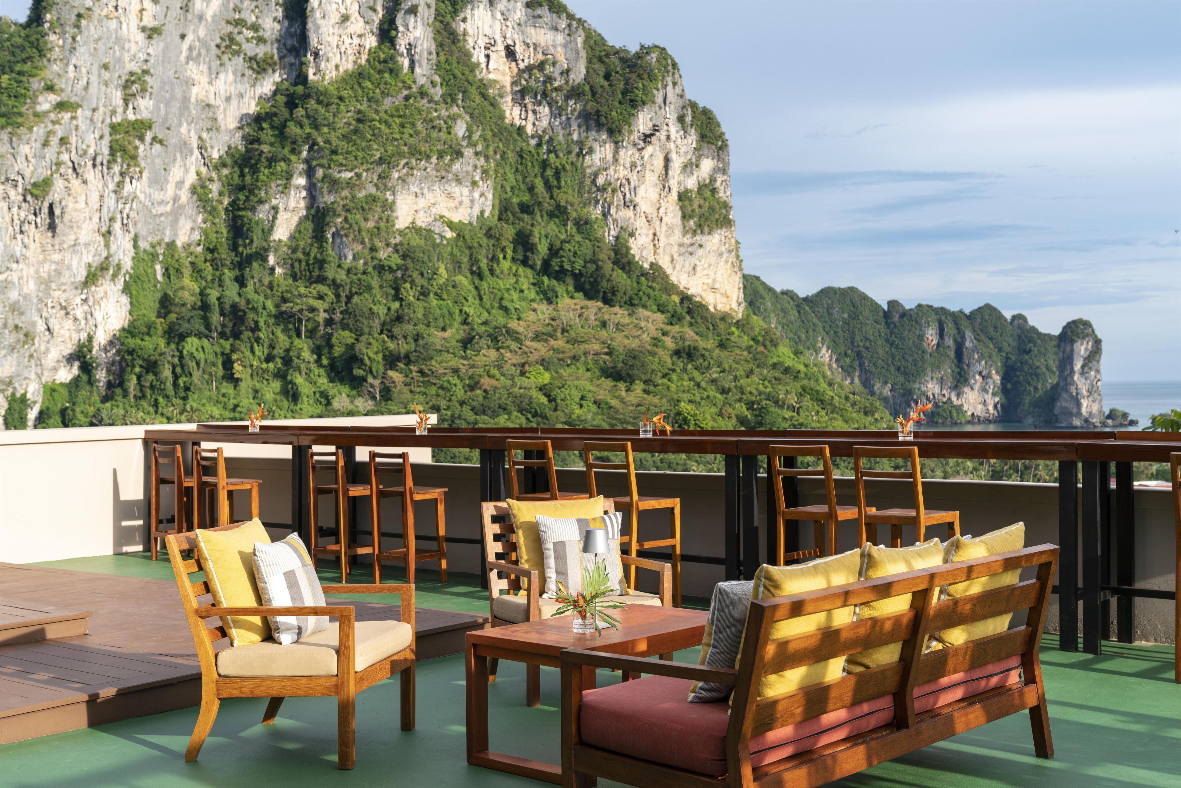 A terrace with wooden furniture and a view of a mountainous landscape.