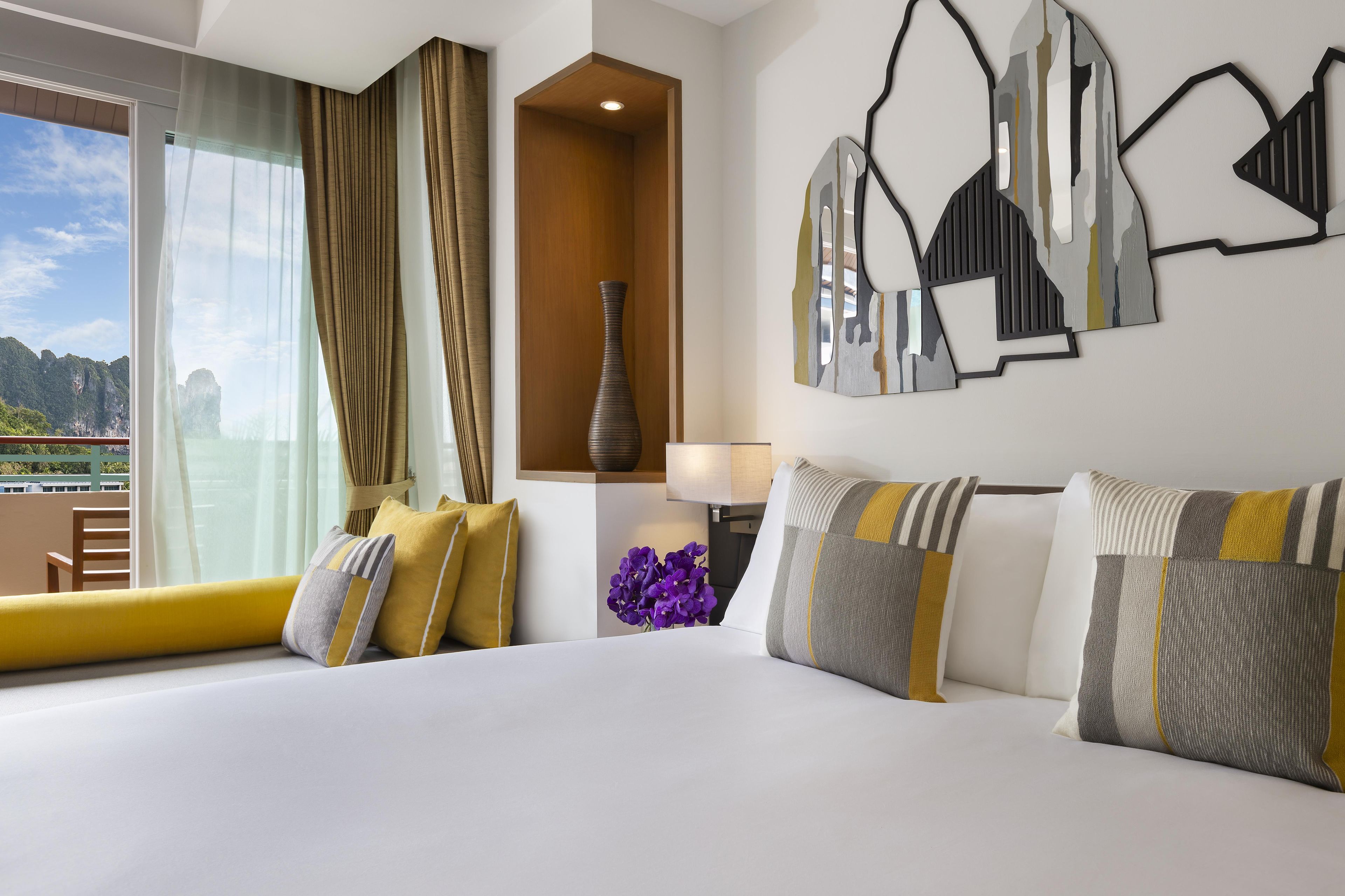 Habitación de hotel con una cama grande, un florero y vistas al exterior.