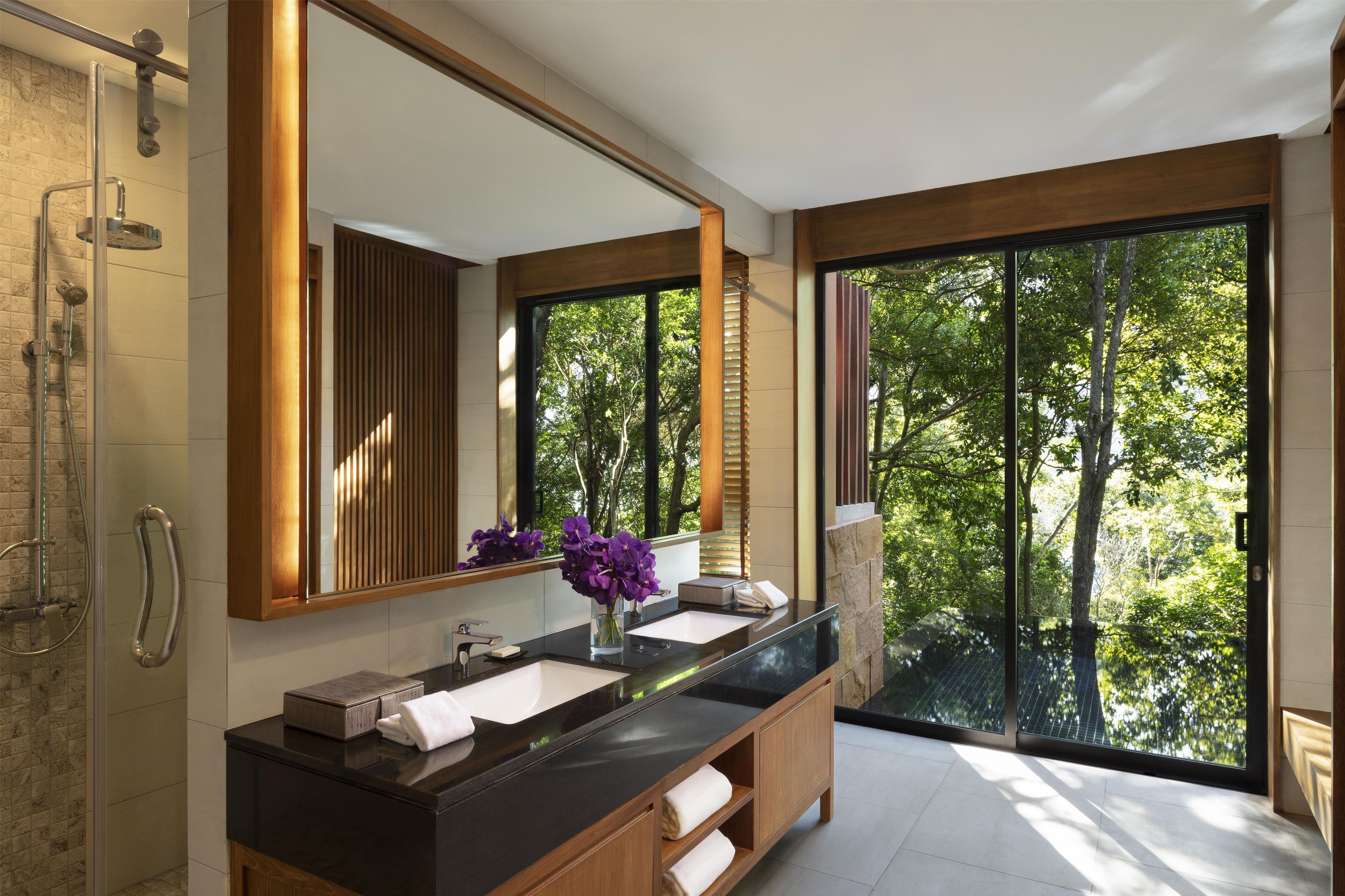 A modern bathroom with a large mirror, a dual sink vanity, and a shower area.