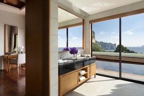 Une salle de bain moderne dotée d’une grande fenêtre, d’un meuble-lavabo en bois et offrant une vue sur un paysage montagneux.