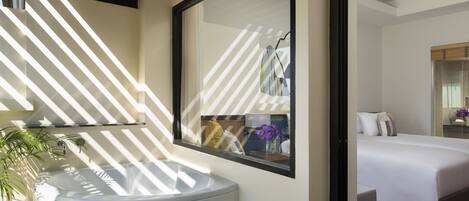 Un baño moderno con un espejo grande, un lavabo redondo y una planta en maceta.