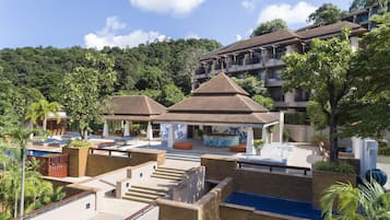 A resort with multiple swimming pools, outdoor seating areas, and a large building with balconies.