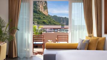 Habitación de hotel con balcón, cama y vistas a un paisaje montañoso.