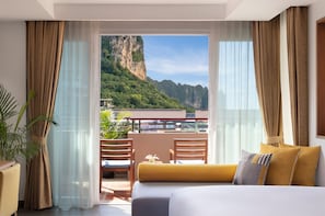 Habitación de hotel con balcón, cama y vistas a un paisaje montañoso.