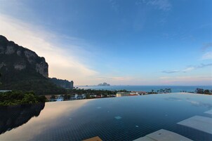 An infinity pool with a view of the ocean and a mountain.