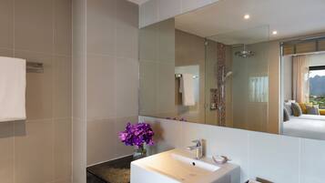 A modern bathroom with a large mirror, a white sink, and a shower area.