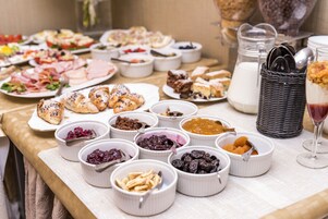 Un tavolo da buffet con diversi cibi e un bricco del latte.