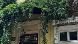 A building facade with a wooden door, a sign reading "KARMEL", and a window with a flower box. - Aparthotel Karmel (Kraków)