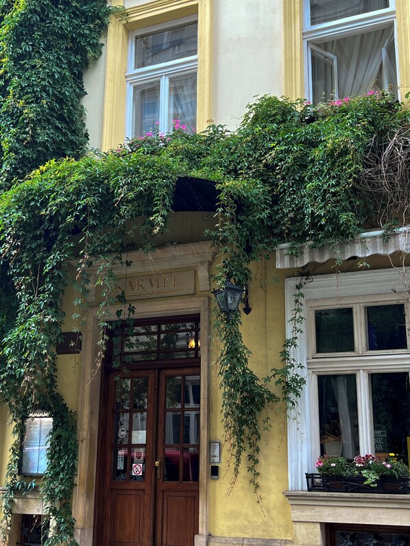 A building facade with a wooden door, a sign reading "KARMEL", and a window with a flower box.