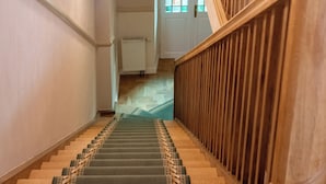 A wooden staircase with a patterned carpet leading to a landing. - Aparthotel Karmel (Kraków)