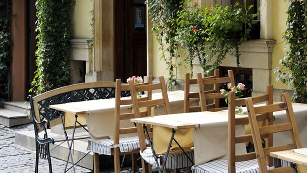 An outdoor seating area with a table and chairs, a hanging lantern, and a window with a view of the street. - Aparthotel Karmel (Kraków)