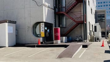 A hotel entrance with a tiled facade, a red fire escape, and a bicycle parked outside.