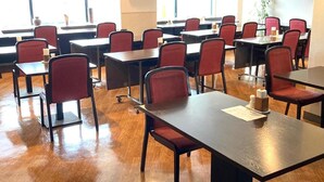 Une salle de conférence équipée de tables et de chaises, de grandes fenêtres et d’un téléviseur à écran plat fixé au mur.