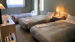 Une chambre d’hôtel avec deux lits, un bureau, une lampe et un téléphone.