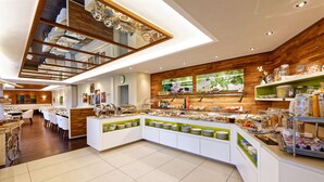 A modern breakfast buffet with a variety of food options, a clock on the wall, and a wooden accent wall. - CASCADA Rheine by Hackmann (Rheine)