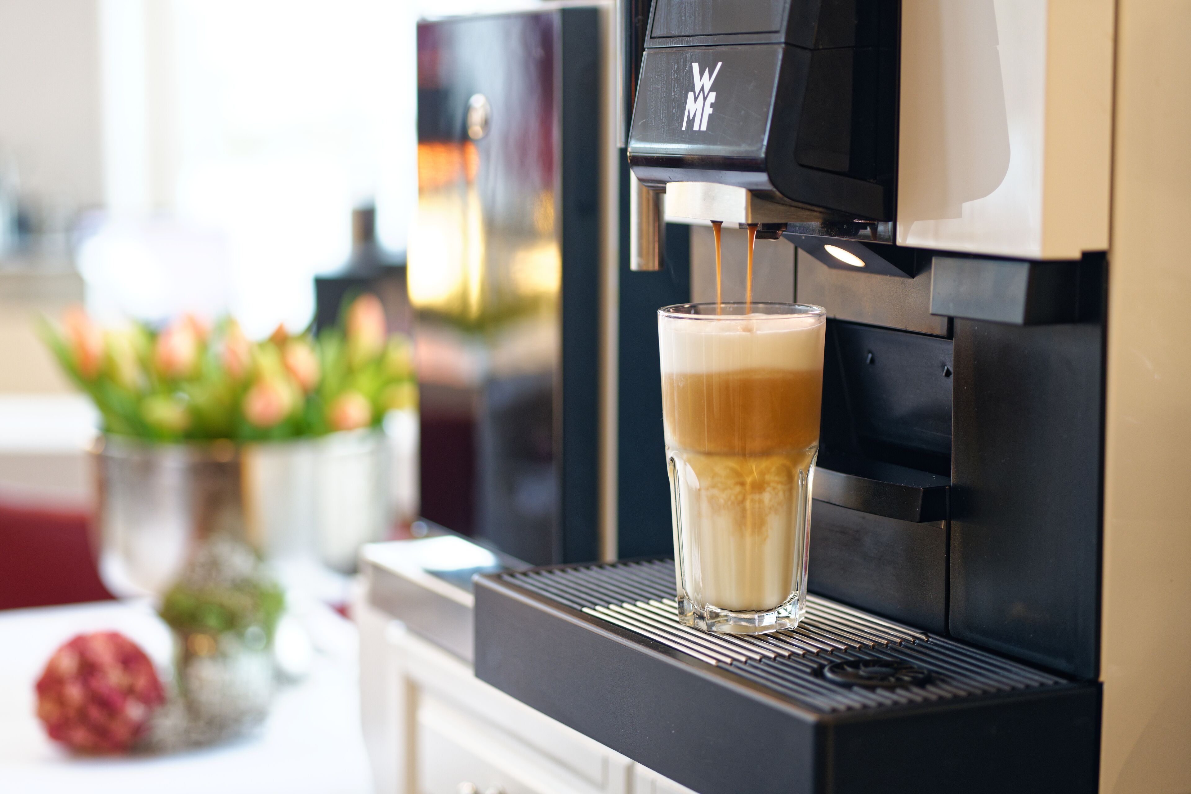 Eine Kaffeemaschine, die ein Getränk in ein Glas füllt.