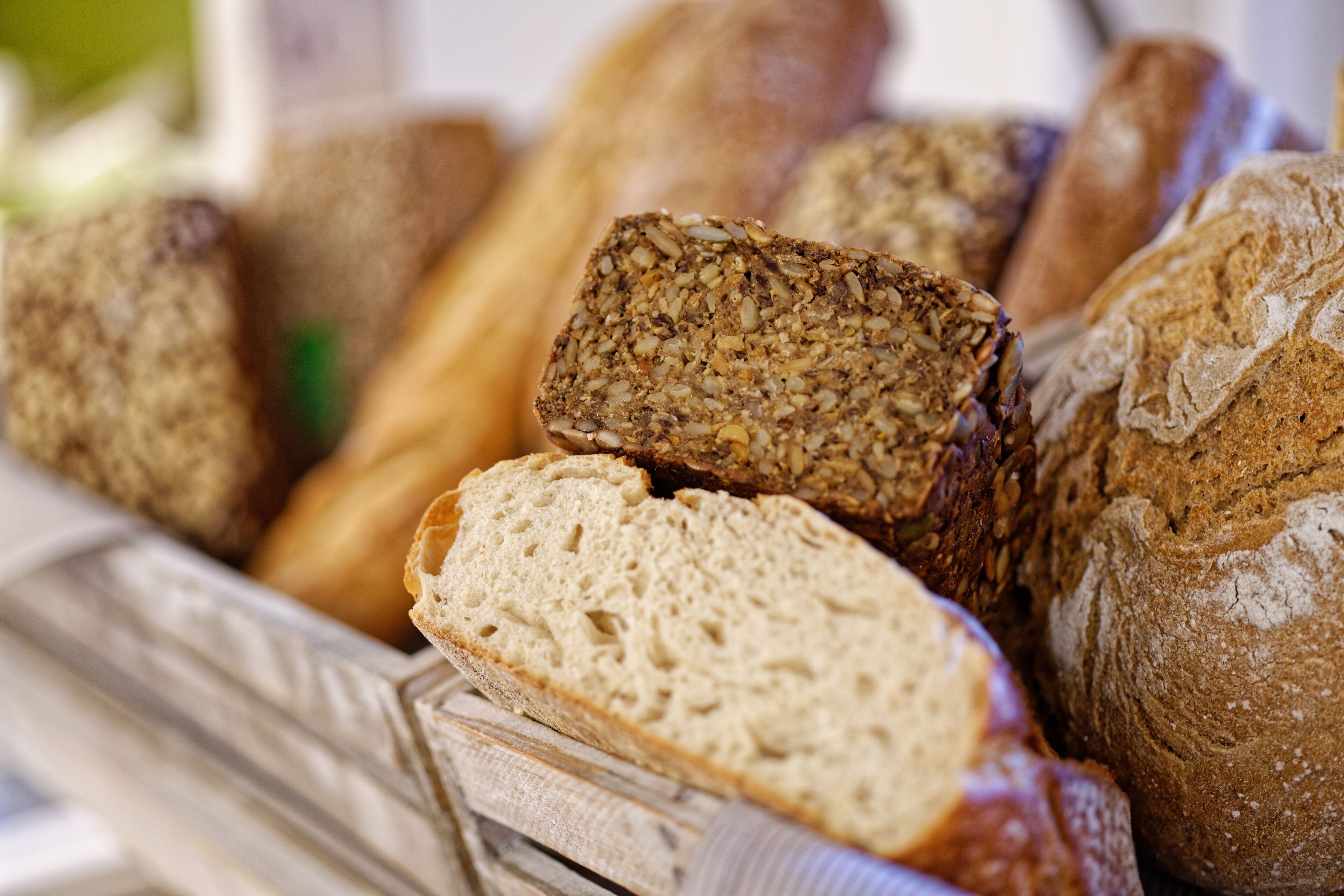 A variety of breads, including whole grain and white bread, displayed in a basket.