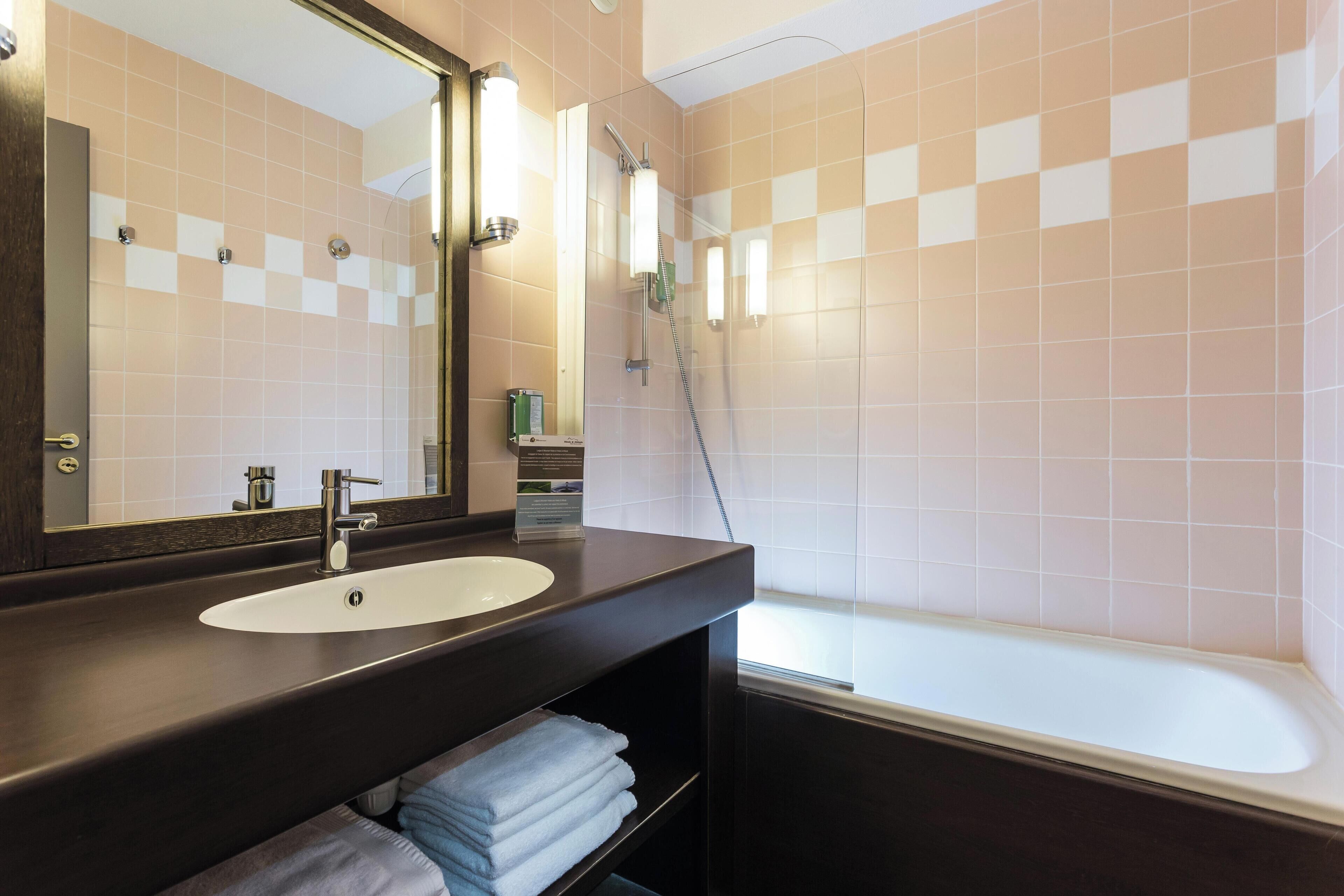 A bathroom with a sink, mirror, and shower.