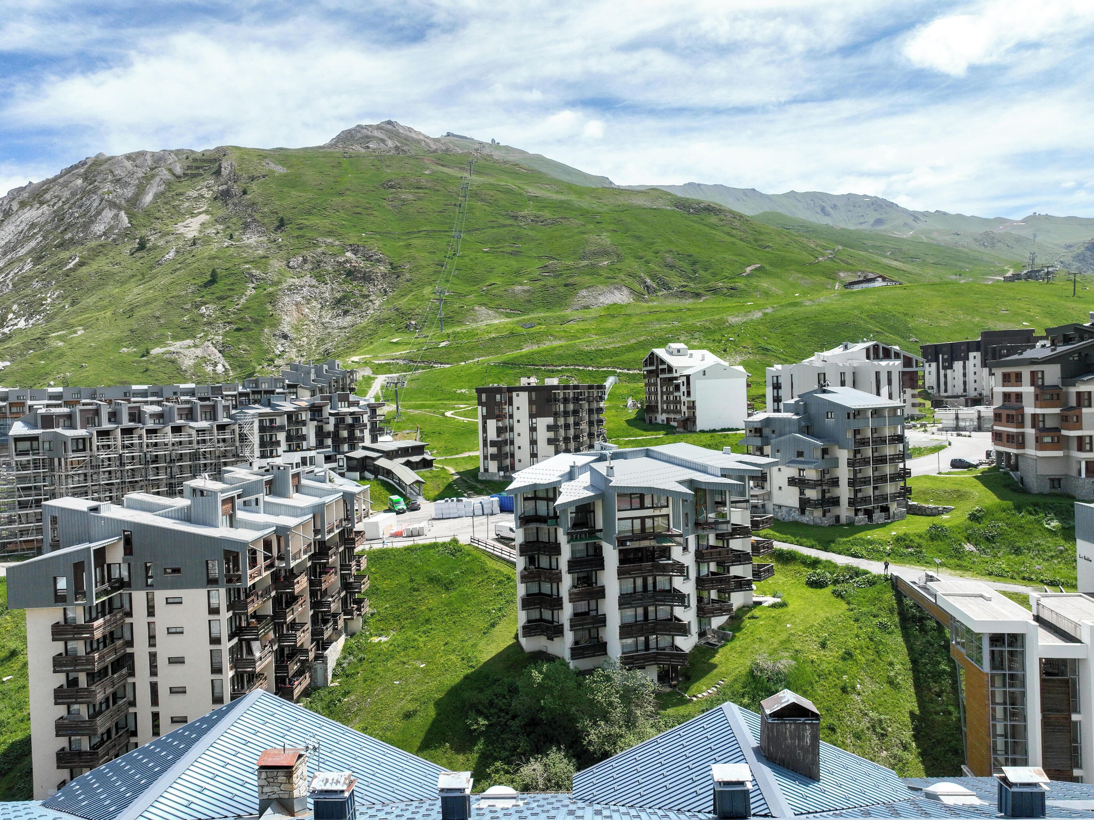 A residential area with modern apartment buildings, green lawns, and a mountainous backdrop.