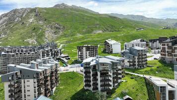 A residential area with modern apartment buildings, green lawns, and a mountainous backdrop.