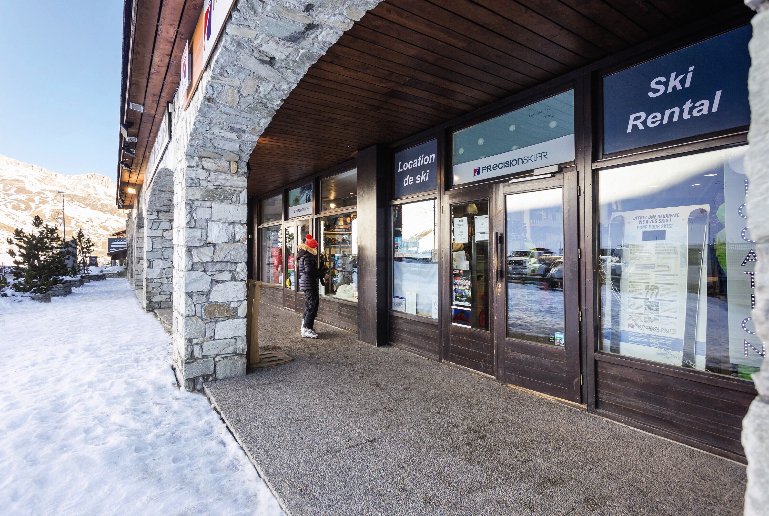 A ski rental building with stone walls and wooden beams, featuring signage for ski location and rental services.