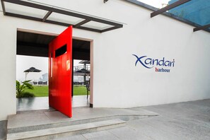 L'ingresso di un edificio moderno con una porta rossa e un cartello con la scritta 'Xandari Harbour'.