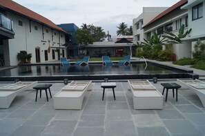 A pool area with lounge chairs and a small table, surrounded by buildings with a tiled roof and a sign that reads "Dora." - Xandari Harbour Fort Kochi (Kochi)