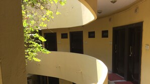A multi-level interior with a curved balcony, multiple doors, and a tiled floor. - Hotel Mewar Inn (Udaipur)