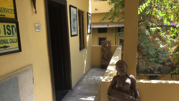 A corridor with a statue, a sign for 'ISD National Calls', and a door leading to another room. - Hotel Mewar Inn (Udaipur)