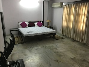 A bedroom with a bed, a nightstand, a lamp, and a window with curtains.