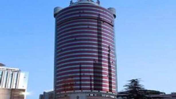 Un edifici alt i cilíndric amb franges horitzontals, probablement un hotel o un edifici de oficines, envoltat d'altres edificis.