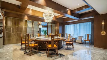 A modern dining area with a round table, wooden chairs, and a chandelier.