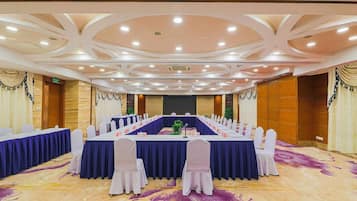 A conference room with a long table, white chairs, and a carpeted floor.