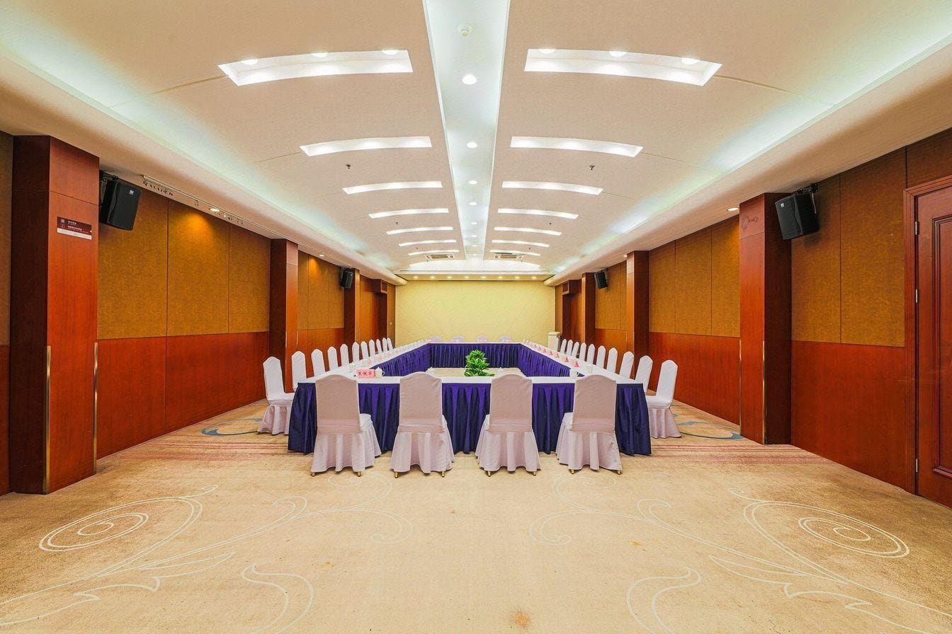 A conference room with a long table, white chairs, and a blue tablecloth.