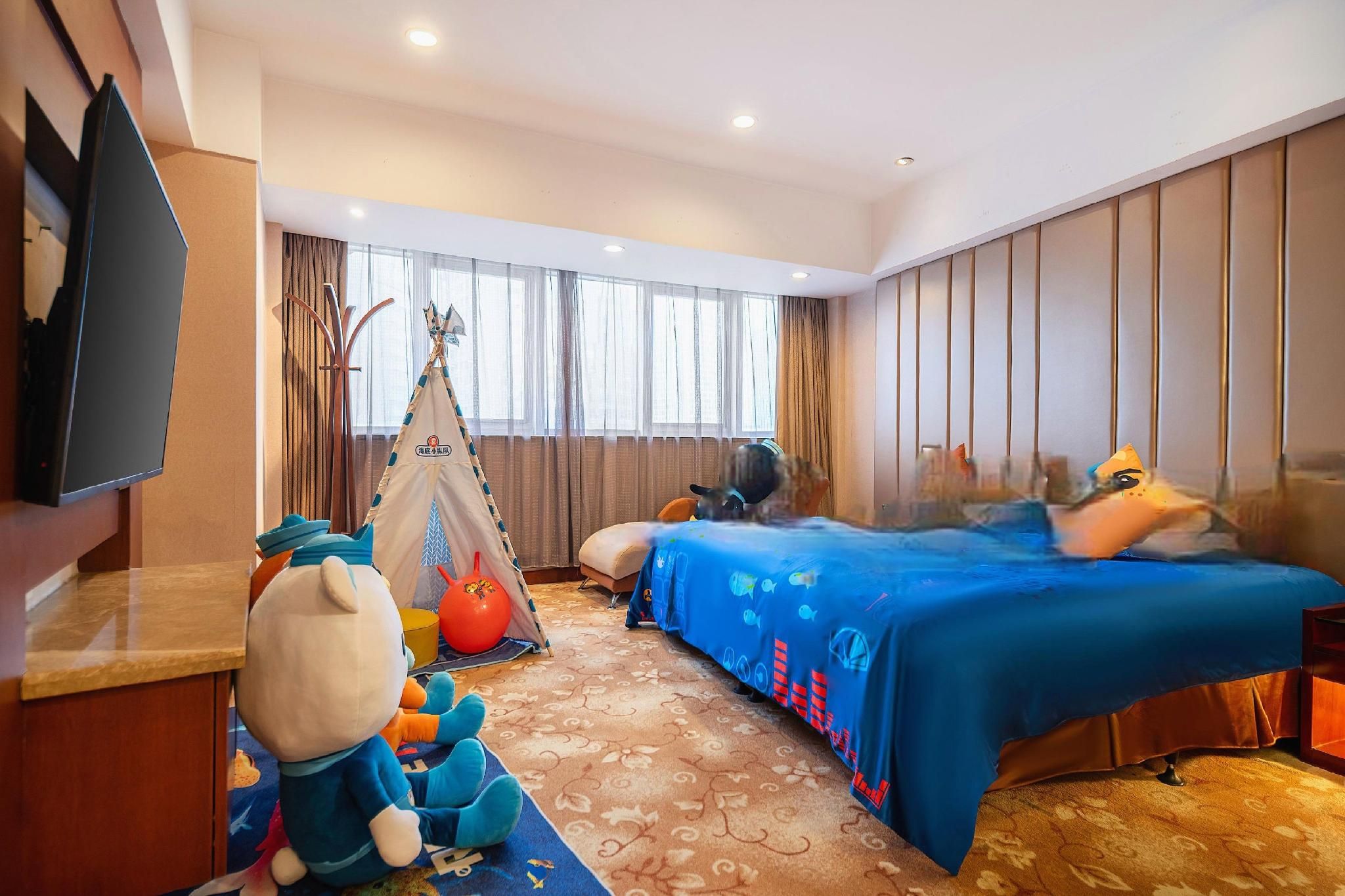 Une chambre d’hôtel avec un lit, une télévision, une tente et des peluches.