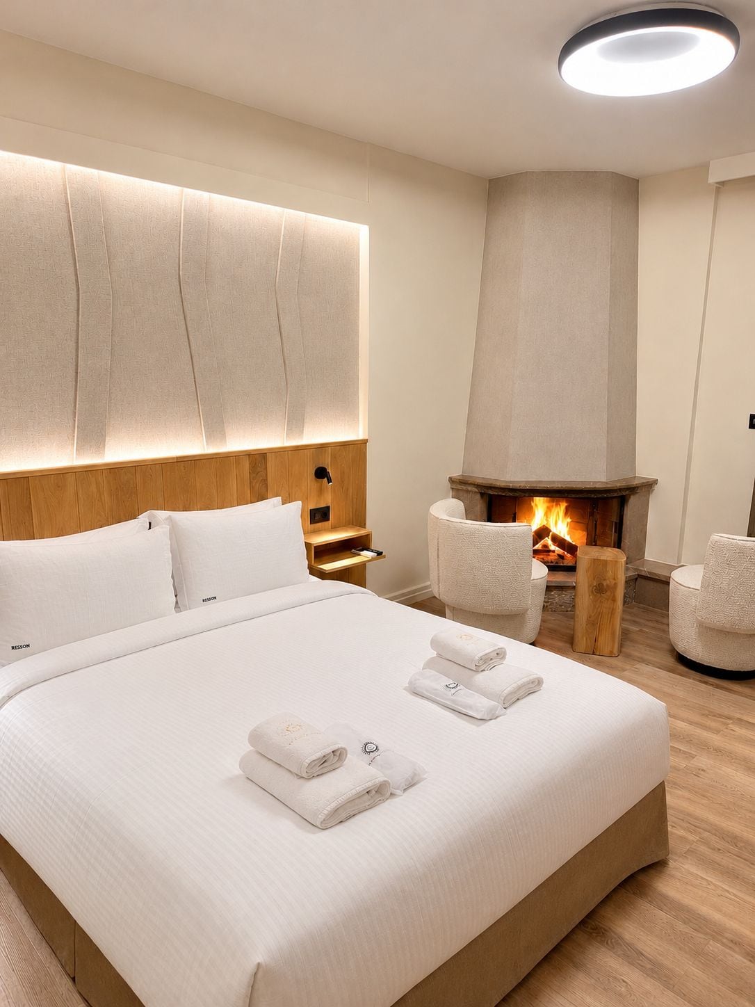 Een moderne hotelkamer met een groot bed, een open haard en een zithoek.