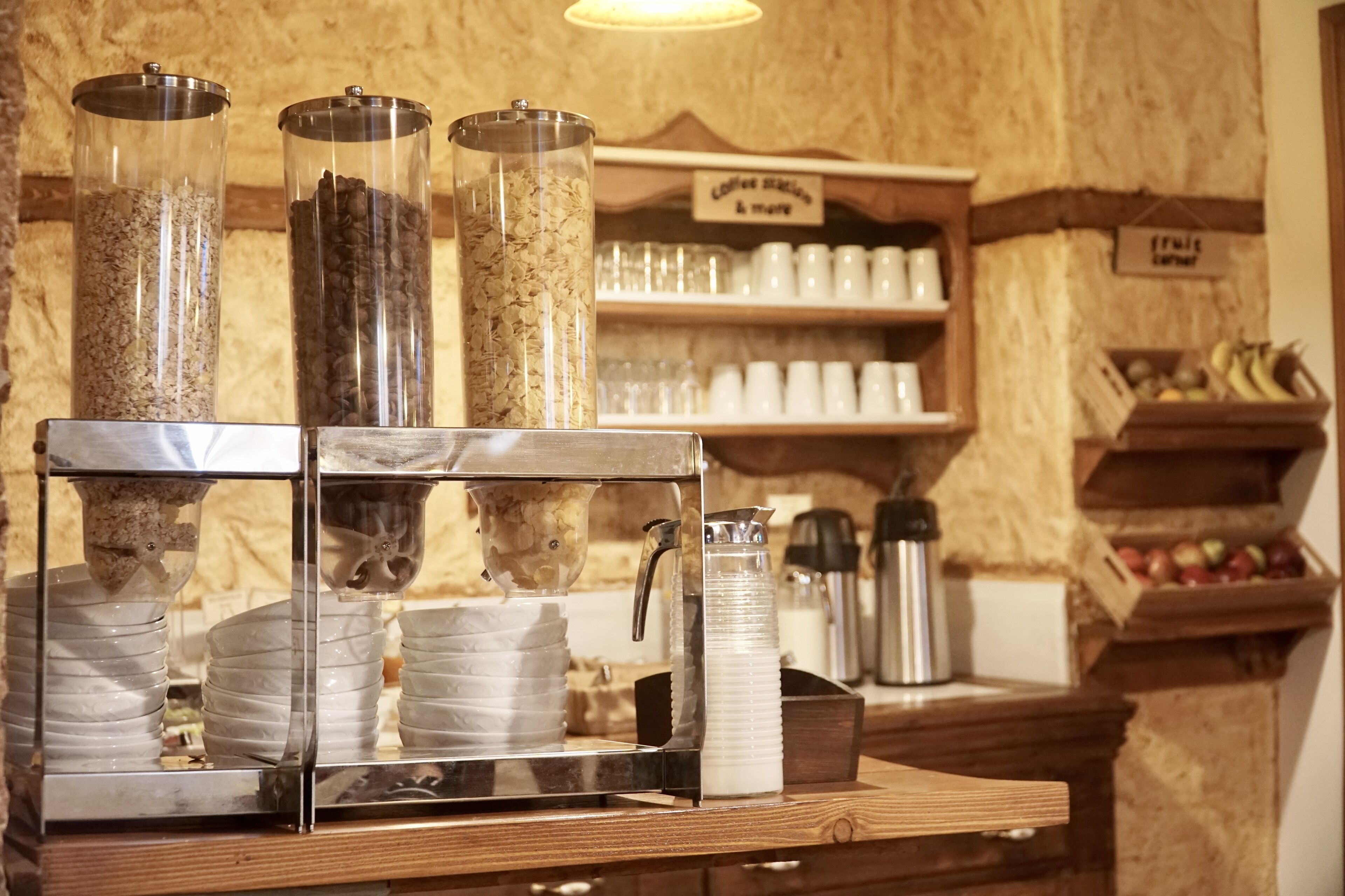 Una estación de café con una cafetera, espumador de leche y recipientes con granos de café y leche.