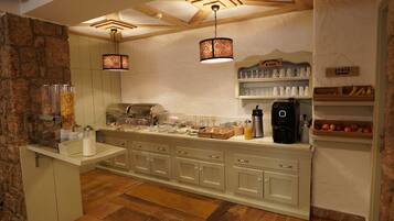 A kitchen with a stone wall, wooden ceiling, and a long counter with various appliances and food items.