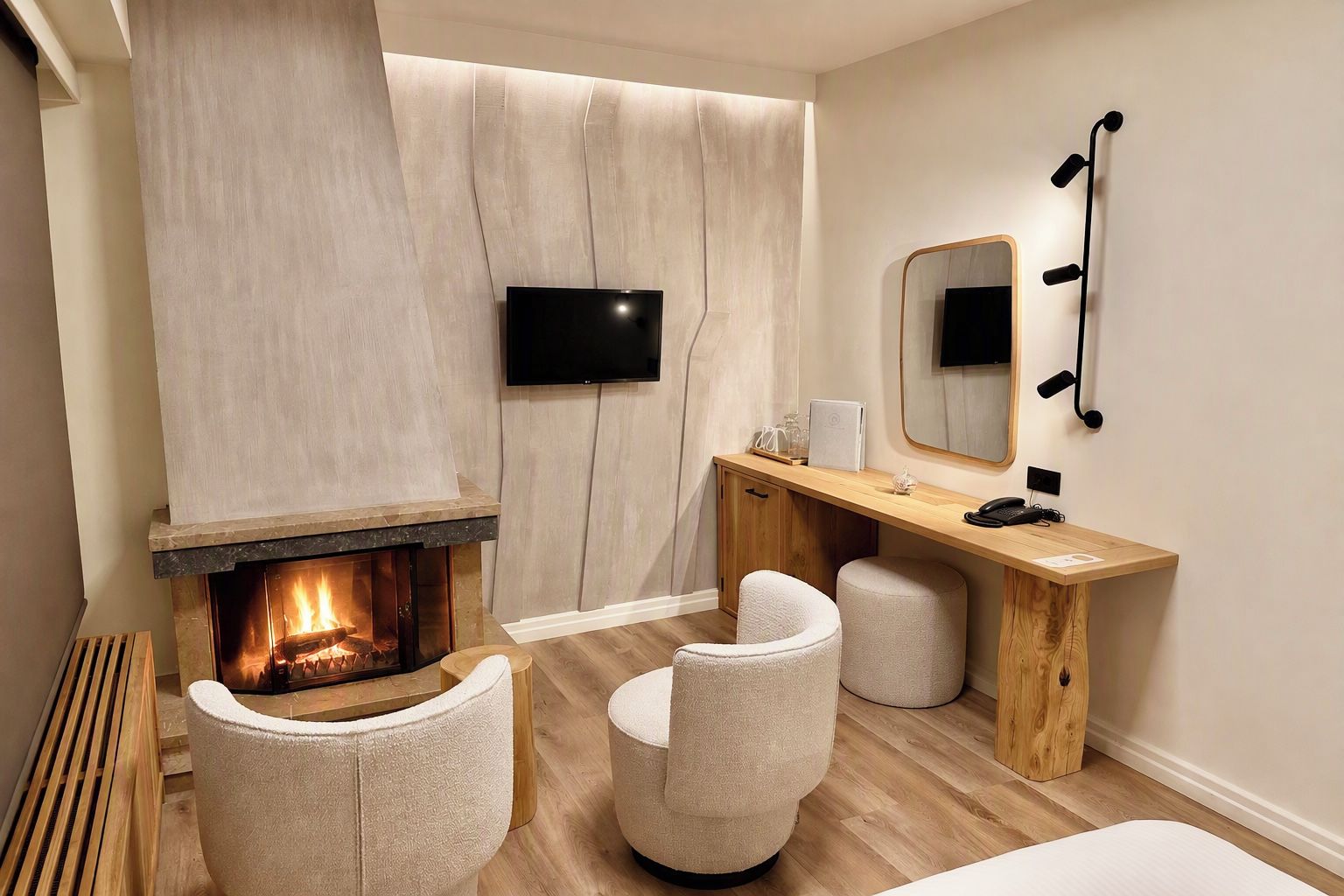 Une salle de bain moderne avec une cheminée, un meuble-lavabo en bois, deux chaises et un miroir.