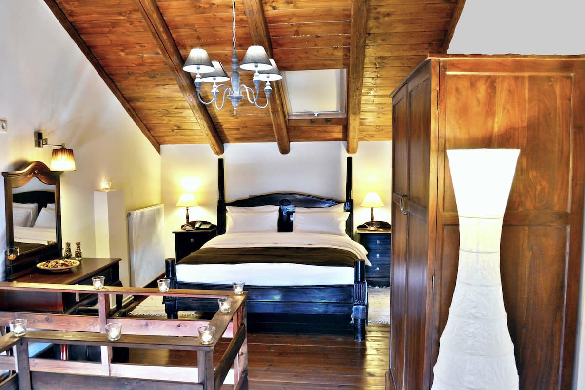 Une chambre avec un plafond en bois, un grand lit, des lampes de chevet, un miroir et un radiateur.