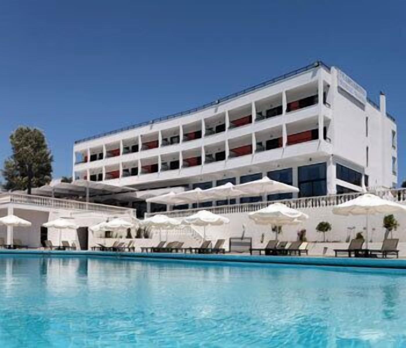 A multi-story hotel with a swimming pool and sun loungers.